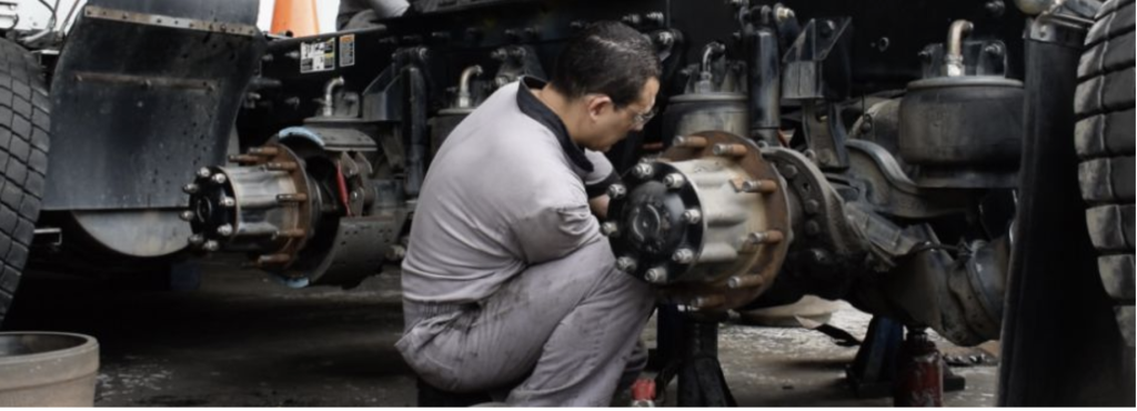 Mecánico trabajando en el eje de un camión en un taller.