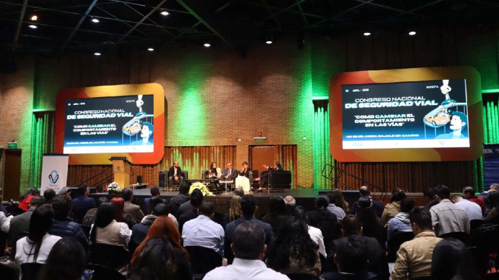 Personas asistiendo a un congreso sobre seguridad vial con una pantalla grande que muestra el tema principal del evento.