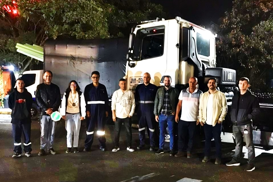 Un grupo de personas posa frente a un camión estacionado durante la noche.