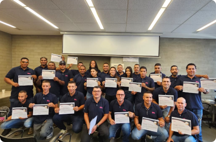 Un grupo de personas sonrientes sostiene certificados en una sala de reuniones.