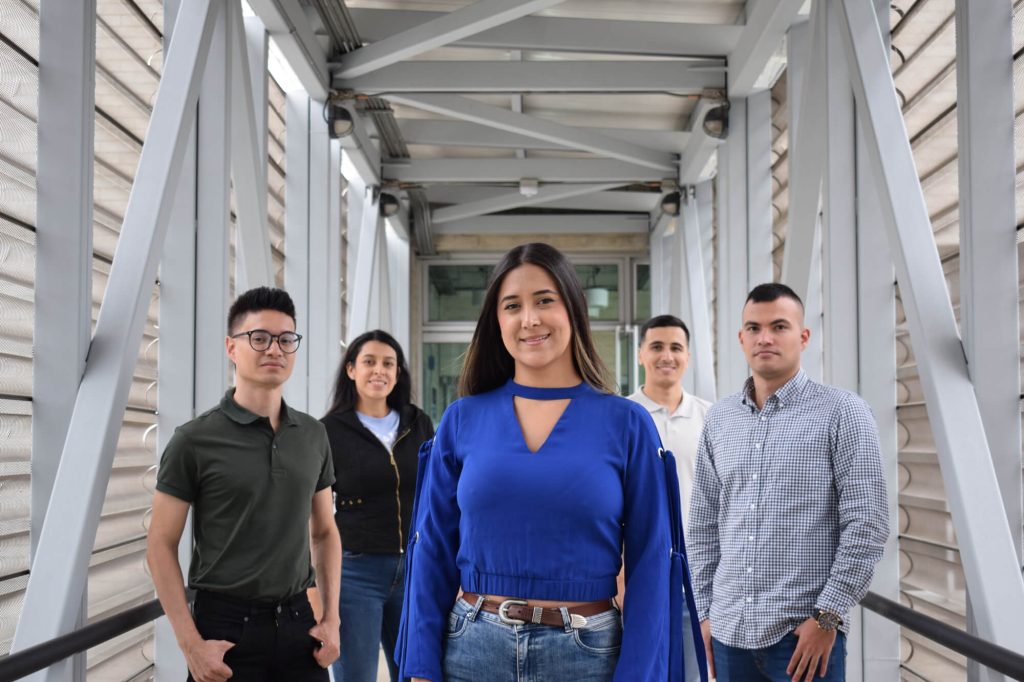 Un grupo de cinco personas posando en un pasillo de estructura metálica.